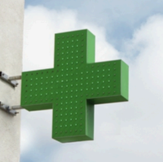 Croce farmacia LED installata a bandiera su parete esterna in luce diurna