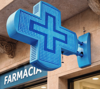 Croce farmacia LED blu installata in sporgenza su facciata con insegna farmacia